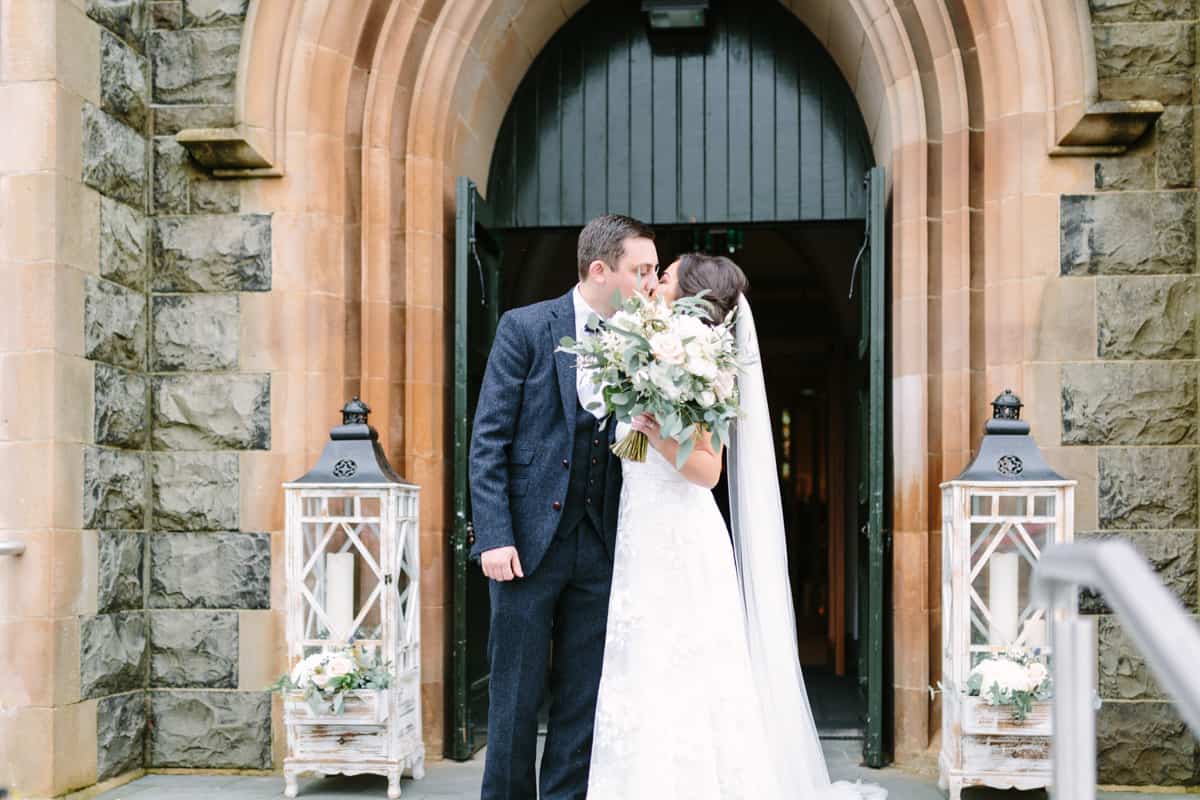 Bride and groom kissing at church door