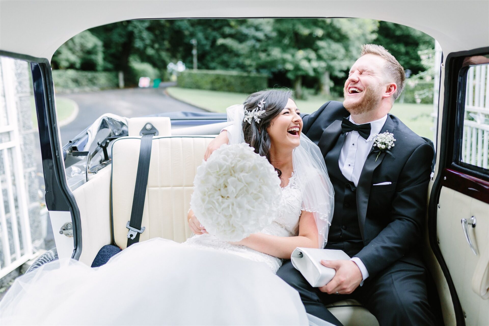 Bride and groom laughing in wedding car
